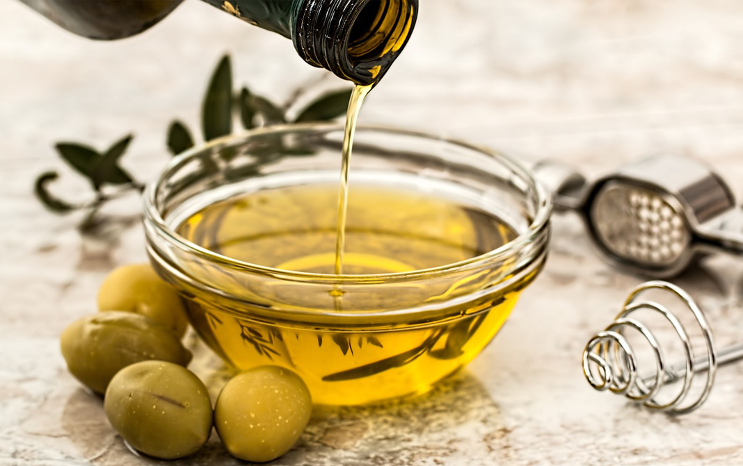 Olive oil being poured into a glass bowl
